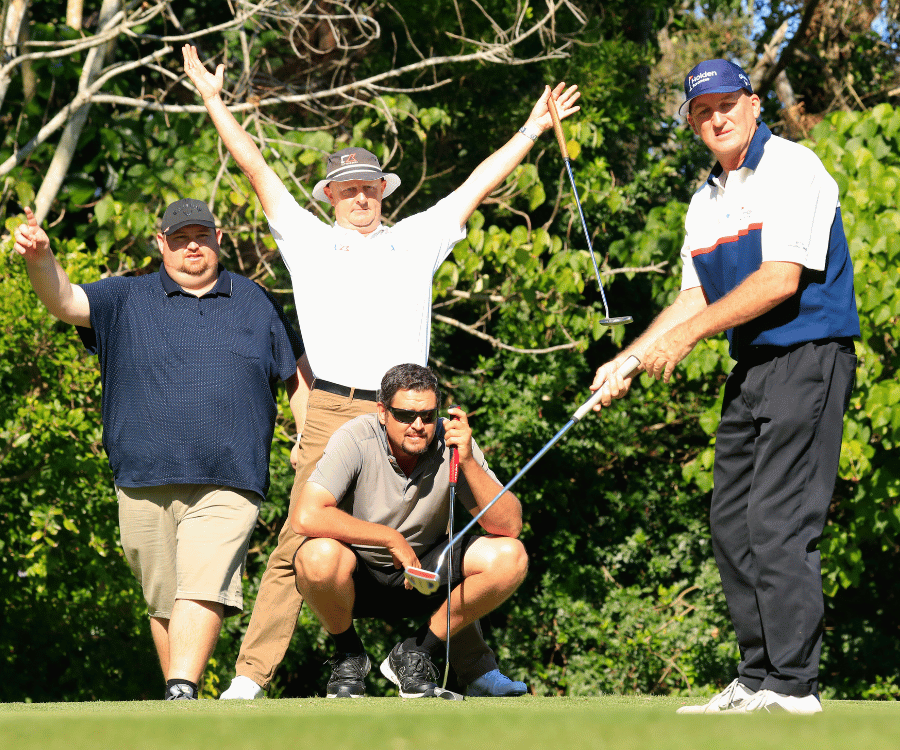 Four men on a golf course, one putting while others watch