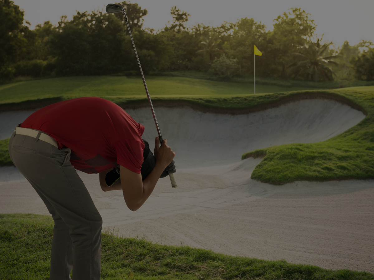Golfer frustrated near sand trap with club