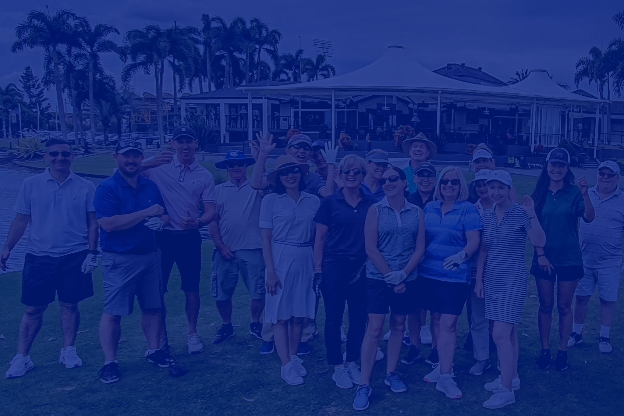 Group of people posing on a golf course with clubhouse in background